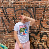 a young man standing in front of a graffiti covered wall